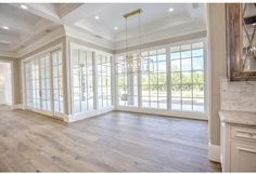 an empty living room with wood floors and large windows