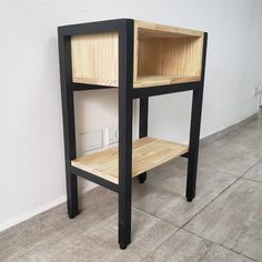 a black and wood shelf sitting on top of a floor next to a white wall