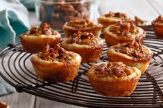 several small muffins are cooling on a wire rack with some nuts in the middle