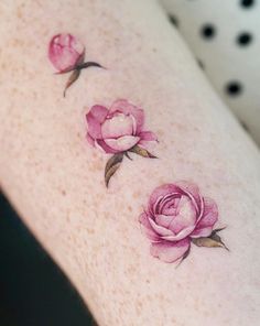 a woman's arm with three pink roses on the left side of her body