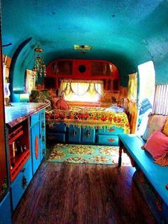 the interior of an rv with blue walls and wood flooring is decorated in bright colors