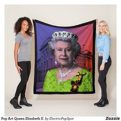 two women standing next to each other holding up a queen elizabeth tapestry