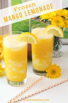 two glasses filled with lemonade sitting on top of a table next to yellow flowers