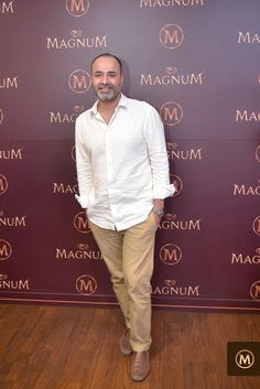 a man standing in front of a wall with the words magnaium on it and his hands in his pockets