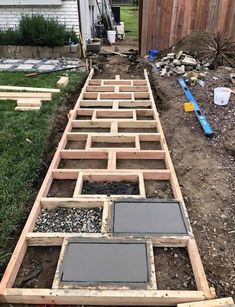 an outdoor walkway made out of wood and concrete blocks in the yard with tools laying around it