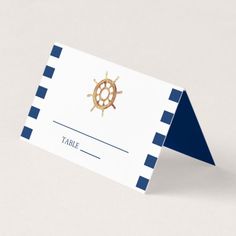 a place card with a ship wheel on the front and navy blue border around it