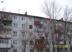 an apartment building with balconies and trees in the foreground on a cloudy day