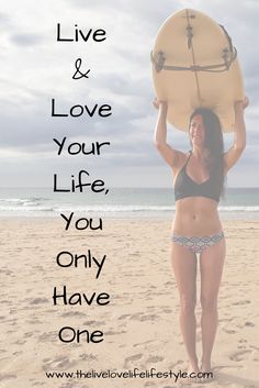 a woman holding a surfboard over her head while standing on the beach with text that reads live & love your life you only have one