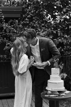 a man and woman kissing in front of a cake