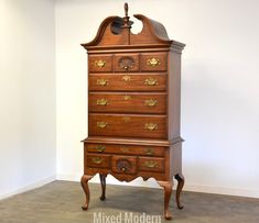 an old wooden dresser sitting in the corner of a room with white walls and flooring