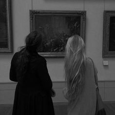 two women looking at paintings in an art gallery