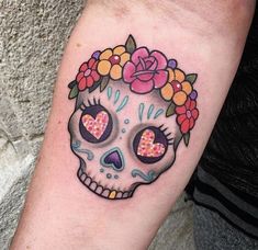 a woman's arm with a skull and flowers on it