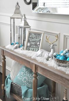 a wooden table topped with blue and white christmas decorations on top of snow covered ground