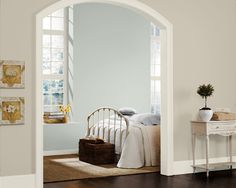 a bedroom with an arched doorway leading to a bed and desk in front of it