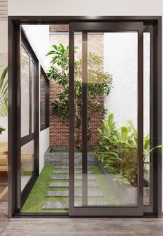 an open glass door leading to a small courtyard with green plants on the side walk