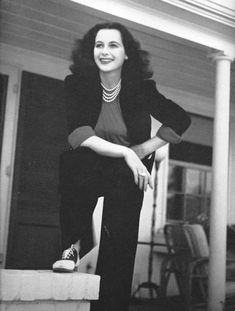 black and white photo of woman sitting on steps with legs crossed, smiling at camera