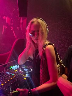 a woman with headphones is playing music on a dj's turntable at a nightclub