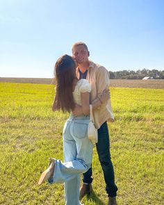 a man standing next to a woman on top of a lush green field