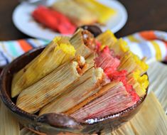 corn on the cob with red sauce in a wooden bowl next to other plates