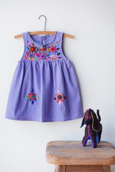 Our colorful Jardinita dresses are made of cotton are hand-embroidered making each one unique! Dresses are sleeveless and come with a button and loop on the back of neckline to secure. - available in sizes 0-4, 6 & 8 see size chart for measurements - as these are all one of a kind embroidery, color may differ from photo - color of dresses may vary depending on dye lots - washing in cold water + hang dry recommended - Made in Guatemala Embroidery Frocks, Vintage Embroidery Designs, Baby Cut, Purple Embroidery, Girls Dresses Diy, Children Dress, Embroidered Scarf, Children Fashion, Carters Girl