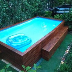 an above ground swimming pool in the middle of a yard with green plants around it