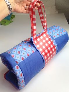 a person is holding a blue and red bag on top of a white countertop