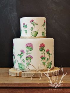 a three tiered cake with flowers painted on it