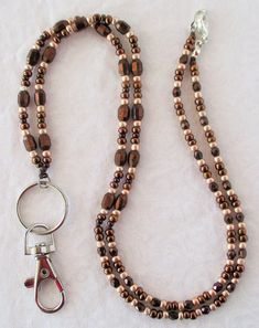 Metallic Brown Beaded Lanyard This Metallic Brown Beaded Lanyard can be used as a badge holder, an I.D. holder, or keychain necklace - it's a multi-use accessory for home or office! 30" in length, long enough to put on or remove overhead. It also has an easy-to-use lobster clasp for your convenience. It's made with metallic brown and light gold glass beads and strong C-Lon beading cord. Snap-on badge holder, clip, and keyring are included to keep your badges or keys ready when you need them. Thi Adjustable Brown Lanyard As Gift, Beaded Lanyards Badge Holders, Keychain Necklace, Beading Cord, Beaded Lanyard, Chain Lanyard, Work Badge, Beaded Lanyards, Id Badge Holders