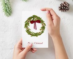 someone holding up a christmas card with a wreath on it