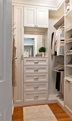 a walk in closet filled with lots of white drawers and shelves next to a door