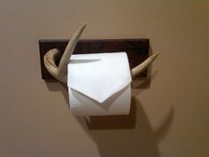 a white toilet paper roll sitting on top of a wooden holder with antlers sticking out of it