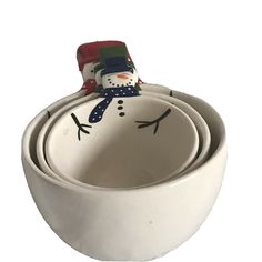 a snowman sitting in a bowl with his head on top of the other bowl