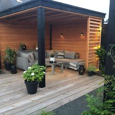 an outdoor living area with couches, tables and potted plants on the deck