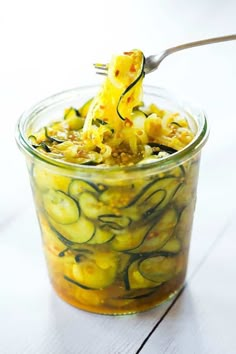 a glass jar filled with pickled cucumbers on top of a white table