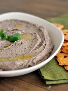 a white bowl filled with hummus next to crackers