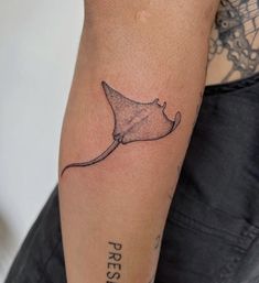 a woman's arm with a tattoo on it that has a small stingfish