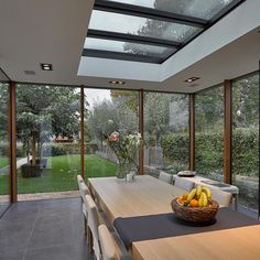 a dining room table with chairs and a bowl of fruit on it