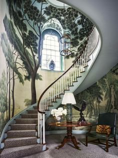 the staircase is painted with trees and flowers on it, along with a table that has two chairs in front of it