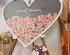 a heart shaped sign sitting on top of a wooden easel next to a vase