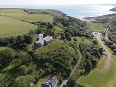 an aerial view of a house in the middle of a green field next to water