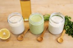 three jars filled with different types of food next to two spoons and some lemon wedges