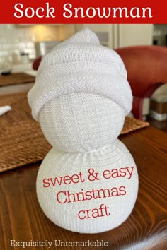 a knitted snowman sitting on top of a wooden table