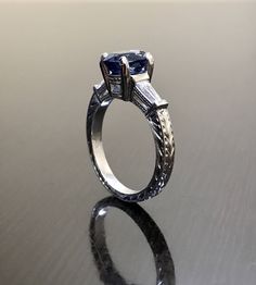 "DeKara Designs Collection Beautiful Modern/Art Deco Ceylon Blue Sapphire and Diamond Ring Metal- 90% Platinum, 10% Iridium Stones- Natural Oval Ceylon Blue Sapphire 2.00 Carats, 2 Baguette Diamonds, F-G Color VS1 Clarity, 0.30 Carats. Size-6. FREE SIZING Classic and Timeless Art Deco Inspired Ceylon Blue Sapphire Oval Diamond Engagement Ring. The center sapphire is a beautiful \"cornflower\" blue in color, and is set in between four prongs with perfection. The center sapphire has a baguette dia Asscher Cut Sapphire Ring With Diamond Cut, Timeless Blue Diamond Cut Ring, Platinum Sapphire Ring With Baguette Cut For Anniversary, Asscher Cut Ring With Polished Finish For Wedding, Polished Sapphire Ring For Wedding, Asscher Cut Wedding Ring With Polished Finish, Classic Blue Round Engraved Ring, Blue Asscher Cut Ring, Heirloom Sapphire Ring With Baguette Cut For Anniversary