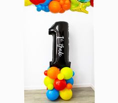 a number one balloon arrangement in front of a white wall with balloons attached to it