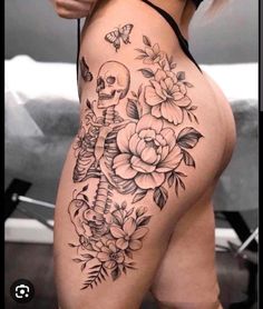 a woman's thigh with flowers and a skull on the side, in black and white