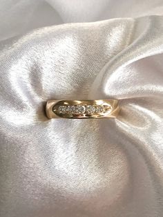 a gold ring with three diamonds sitting on top of a white satin material surface,