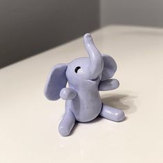 an elephant figurine sitting on top of a white table next to a wall