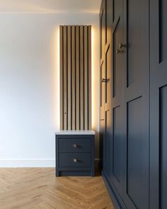 an empty room with a black cabinet and wooden flooring, along with a white striped wall