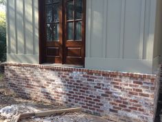 a red brick wall with two doors and some wood planks on the ground in front of it