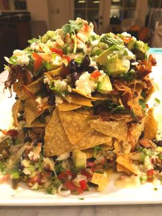 a white plate topped with nachos covered in toppings